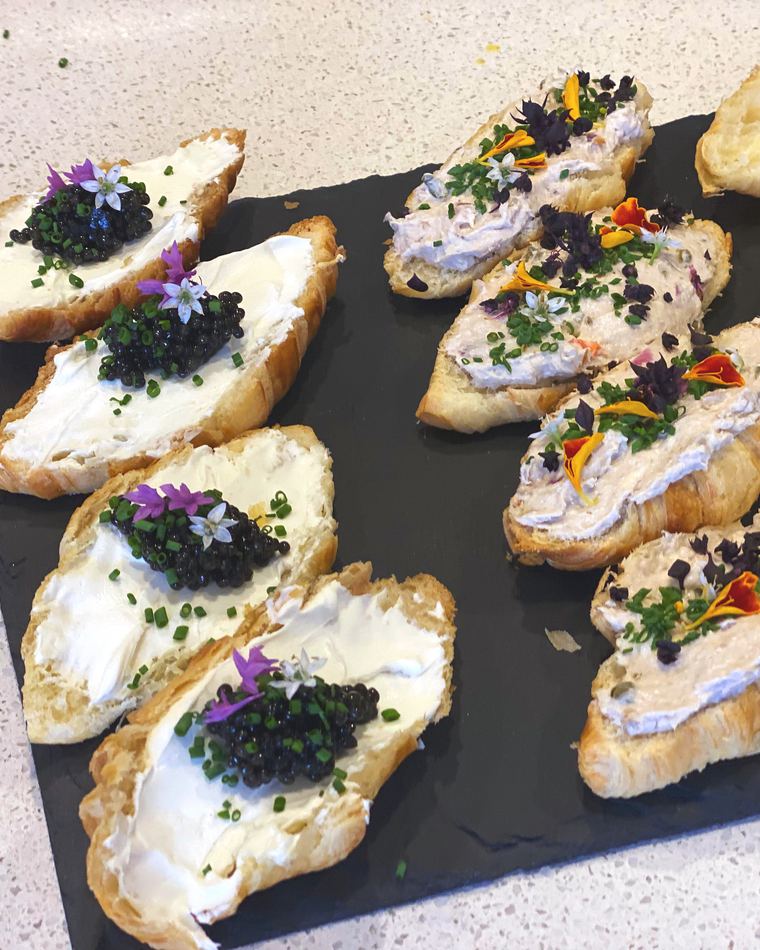 Crostini with caviar and flowers laid out on slate