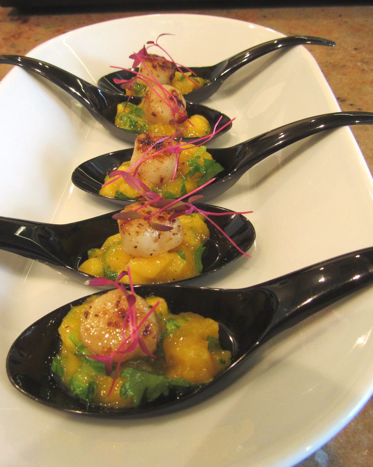 Three black spoons plated with mango and tartare