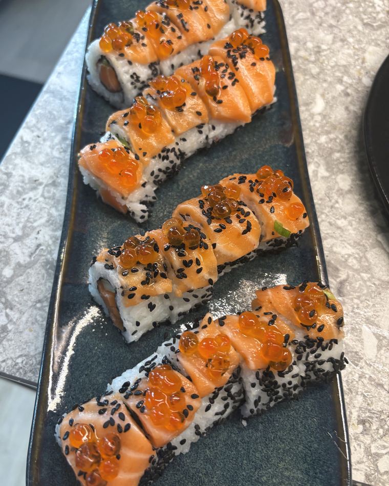 Salmon nigiri with black sesame and roe on dark slate