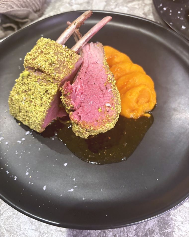 Pistachio-crusted lamb rack with carrot pur&eacute;e on a grey plate