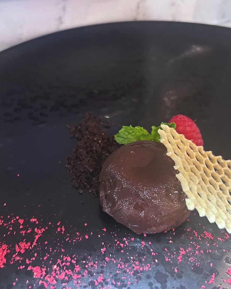 Chocolate quenelle with a honeycomb tuile on a dark plate