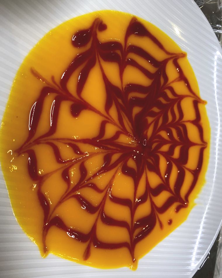 Mango coulis drawn into a web pattern with berry